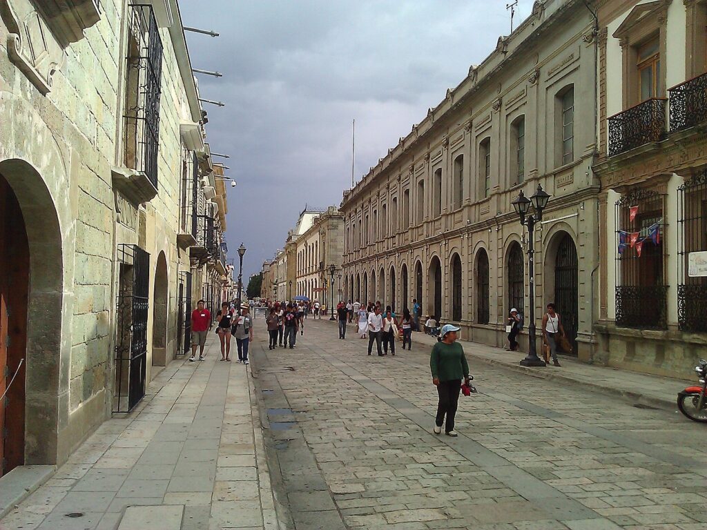 Pedestrians walking along a colonial street in Oaxaca, Mexico